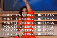 a woman in a red dress is singing a merry christmas song on a television show .