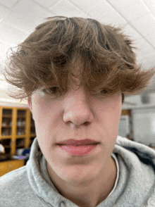 a close up of a person 's face with a gray sweatshirt on