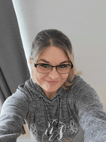 a woman wearing glasses and a grey hoodie with the letters wp on it