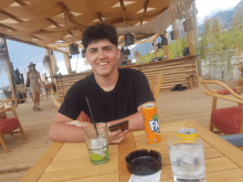 a man sitting at a table with a can of fanta