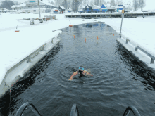 a person swimming in a body of water with a ski lift in the background