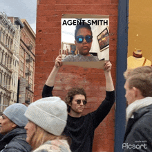 a man holds up a sign with agent smith written on it