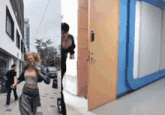 a woman in a pink top is walking down a street next to a door