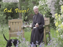 a priest sits on a bench in a garden with a dog and the words canterbury cathedral on the bottom