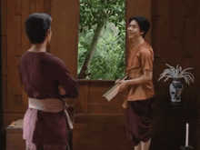 two men are standing in front of a window and one of them is pointing at something