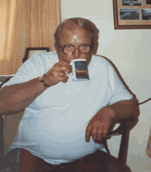 a man with glasses is drinking from a mug with a rainbow design