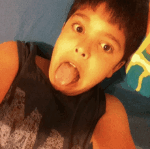 a young boy sticking his tongue out while wearing a black tank top