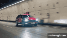 a red car is driving through a tunnel with the make a gif.com website in the background