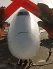 a large white airplane is parked on a runway with a red arrow pointing to the front .