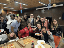 a group of people are posing for a picture with pizza boxes