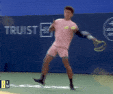 a tennis player is swinging a racket in front of a truist sign