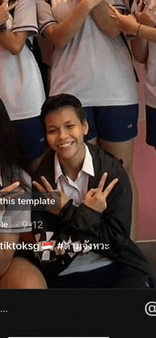 a group of people are posing for a picture and one of them is smiling and giving the peace sign