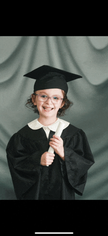 a young girl wearing a graduation cap and gown holds a diploma