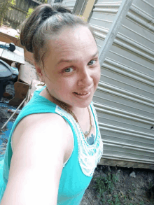 a woman in a blue tank top is smiling in front of a silver trailer