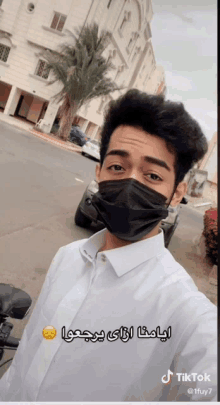 a man wearing a black face mask has a tiktok sticker on his shirt