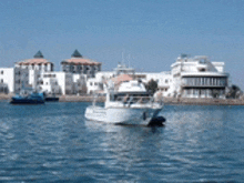 a white boat is floating in the water near a city