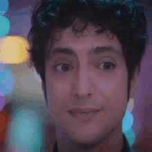 a close up of a man 's face with curly hair looking at the camera with a blurry background .