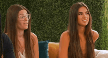 two women with long hair are sitting on a couch