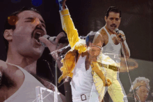 a man with a mustache is singing into a microphone while wearing a white tank top