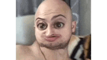 a bald man with a beard is making a funny face with his hand on his chin .