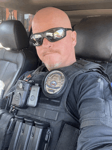 a police officer wearing sunglasses and a vest with a patch that says police officer on it