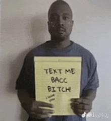 a man is holding a piece of paper that says text me bacc bitch .