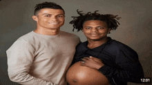 a man holding a pregnant woman 's belly is next to another man with dreadlocks