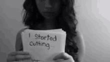 a woman is holding a piece of paper that says i started cutting .