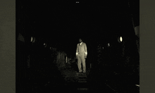 a man in a jumpsuit stands in a dark room