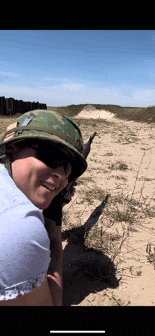 a woman wearing a helmet and sunglasses stands in a field