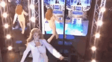 a woman in a white dress is dancing on a stage in front of a television .