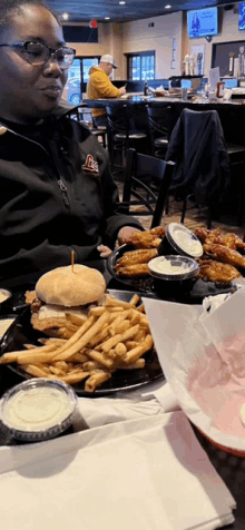 a woman is sitting at a table with a hamburger and fries