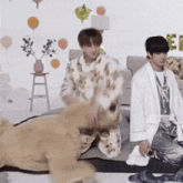 two men in pajamas are playing with a stuffed animal .