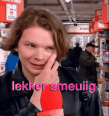 a young man is making a funny face in a store while holding a red object in his hand .