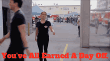 a man and a woman are walking in a parking lot with the words " you 've all earned a day off " above them