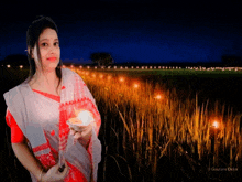 a woman is holding a candle in front of a field of lights