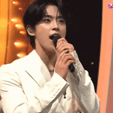 a man in a white suit is singing into a microphone with a purple star in the background