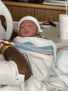 a newborn baby wrapped in a striped blanket is sleeping