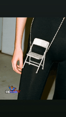 a woman is wearing a purse that looks like a folding chair on a chain