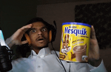 a man holding a can of nestle nesquik