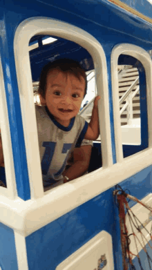 a little boy wearing a number 17 shirt is looking out of a window