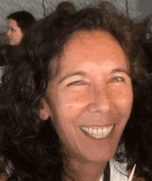 a woman with curly hair is smiling for the camera while holding a pencil .