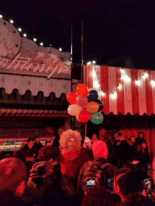 a clown is holding a bunch of balloons in front of a building that says champ