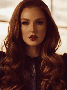 a woman with red hair and red lipstick looks at the camera