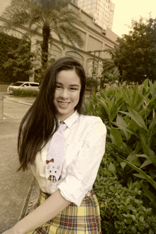 a woman wearing a white shirt and plaid skirt is smiling for the camera