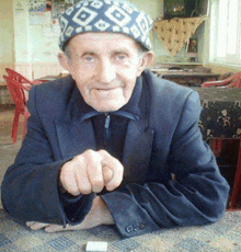 a man wearing a hat with the letter g on it is sitting at a table