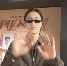 a man wearing sunglasses stands in front of a poster that says ' treasure in japan ' on it