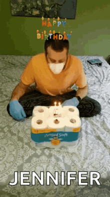 a man wearing a mask and gloves is sitting on a bed with a birthday cake made out of toilet paper