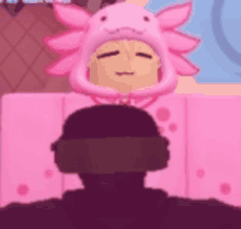 a person wearing a pink axolotl hat and headphones is laying on a pink blanket .