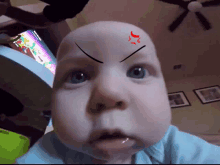 a baby with a red arrow on his forehead